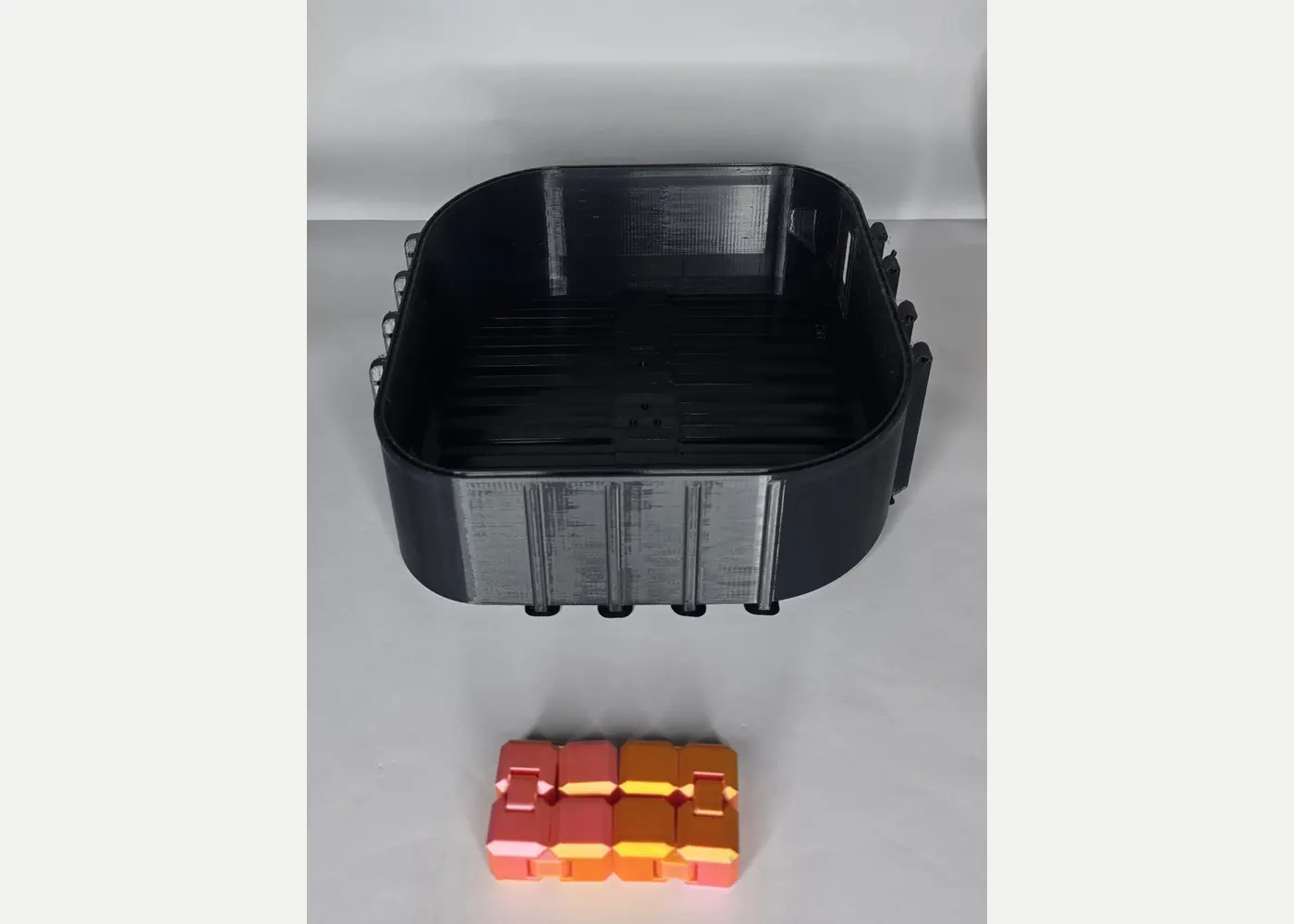 Large black custom 3D printed container with colour samples